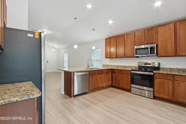 kitchen featuring kitchen peninsula, stainless steel appliances, decorative light fixtures, light wood-type flooring, and sink