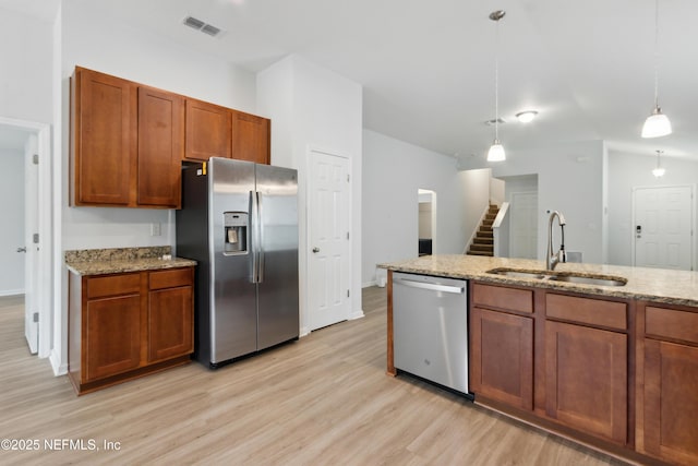 kitchen featuring light stone counters, sink, hanging light fixtures, and stainless steel appliances