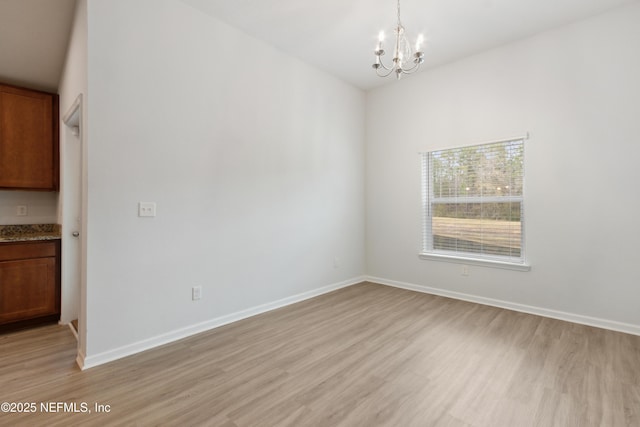 unfurnished room featuring a notable chandelier and light hardwood / wood-style floors