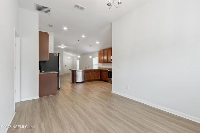 kitchen featuring pendant lighting, appliances with stainless steel finishes, lofted ceiling, light hardwood / wood-style floors, and sink