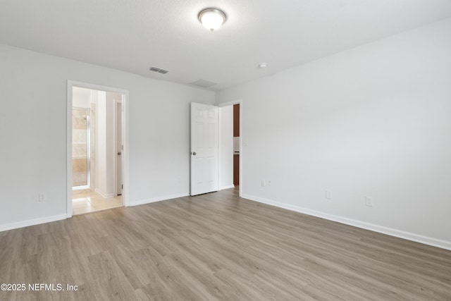 unfurnished bedroom with ensuite bath and light wood-type flooring