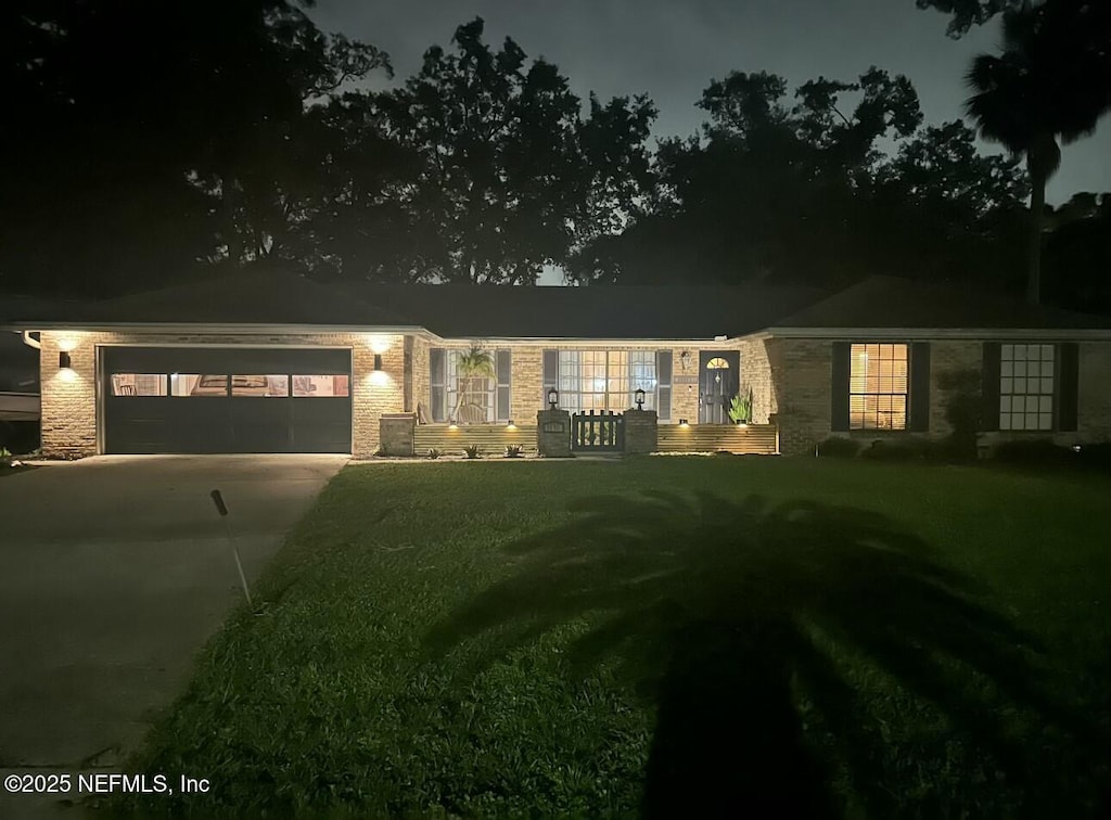 ranch-style house featuring concrete driveway, a yard, and an attached garage