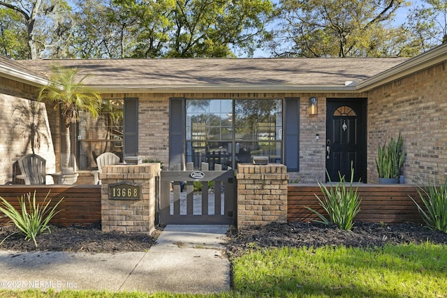 entrance to property with brick siding and a shingled roof