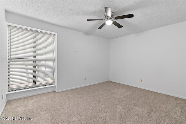 carpeted empty room with ceiling fan, a wealth of natural light, and a textured ceiling