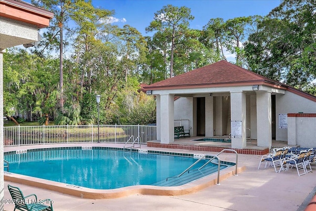 view of pool featuring a patio area, a hot tub, and an outdoor structure