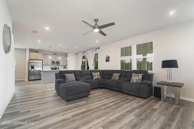 living room with light wood-type flooring and ceiling fan