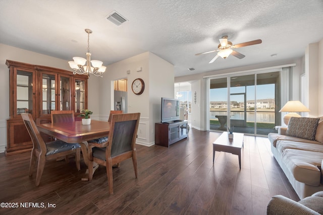 dining space featuring expansive windows, dark hardwood / wood-style flooring, ceiling fan with notable chandelier, and a textured ceiling