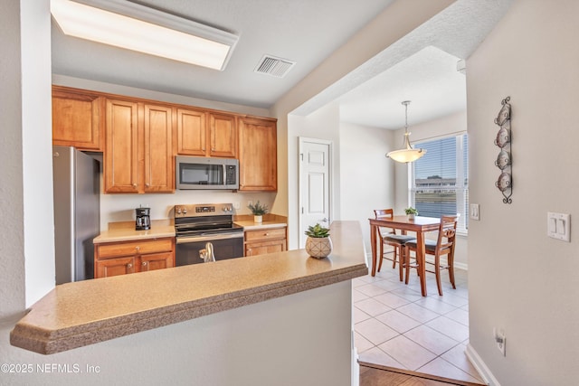 kitchen with decorative light fixtures, stainless steel appliances, kitchen peninsula, and light tile patterned flooring