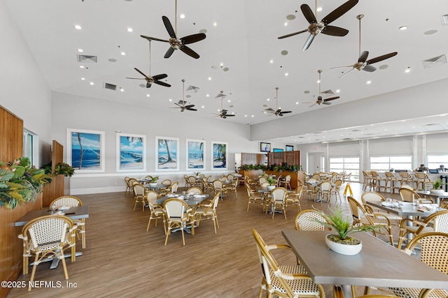 dining area with a towering ceiling and light wood-type flooring