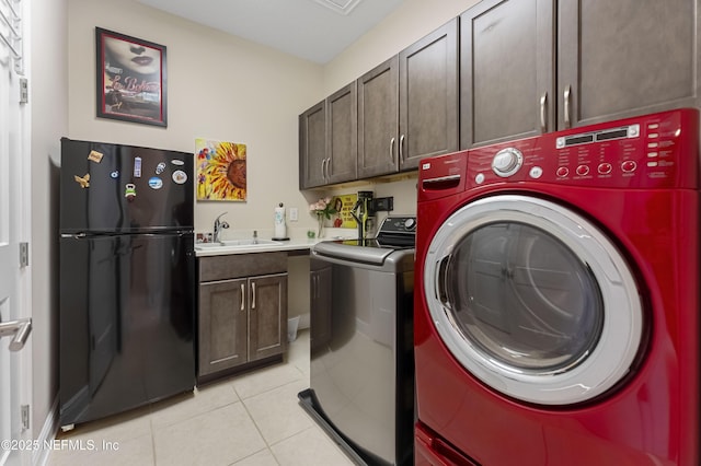 washroom featuring cabinets, sink, washing machine and dryer, and light tile patterned floors