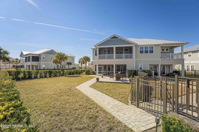 back of house featuring a balcony, a lawn, and a patio area