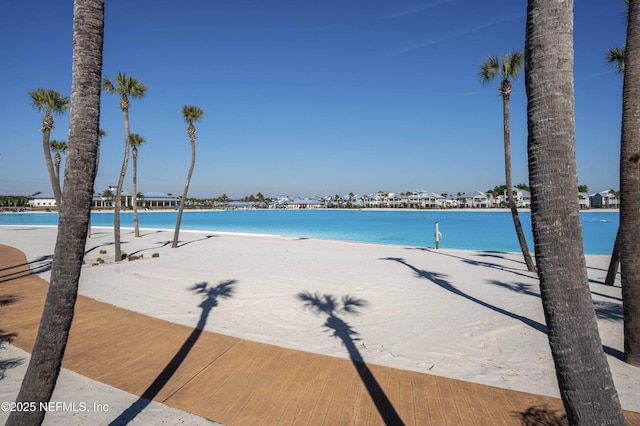 view of swimming pool with a water view and a view of the beach