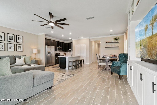 living room featuring light hardwood / wood-style floors, ceiling fan, and ornamental molding