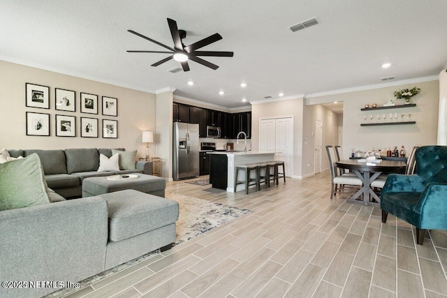 living room featuring ceiling fan, sink, and crown molding