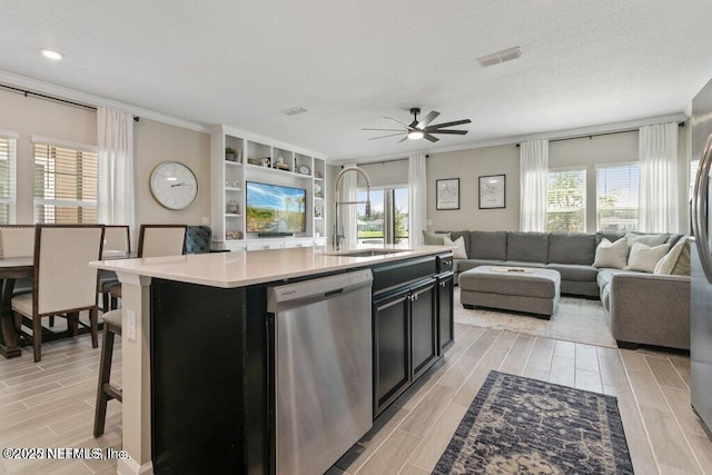 kitchen with dishwasher, sink, a wealth of natural light, a kitchen island with sink, and a breakfast bar area