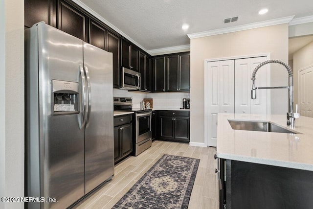 kitchen with appliances with stainless steel finishes, sink, backsplash, light stone counters, and ornamental molding