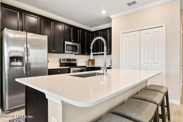 kitchen with sink, a kitchen island with sink, a breakfast bar, and appliances with stainless steel finishes