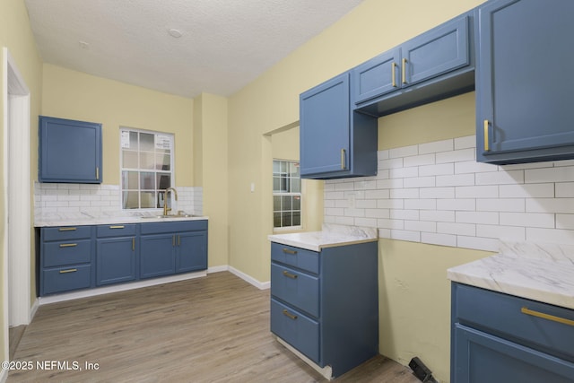 kitchen with blue cabinets, sink, and light hardwood / wood-style flooring