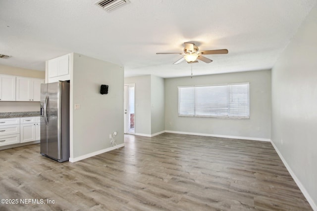 kitchen featuring stainless steel fridge, ceiling fan, white cabinets, light wood-type flooring, and a textured ceiling