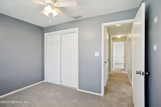 unfurnished bedroom with ceiling fan, light colored carpet, and a closet