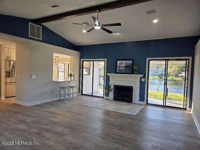 unfurnished living room with vaulted ceiling with beams, wood finished floors, visible vents, and baseboards