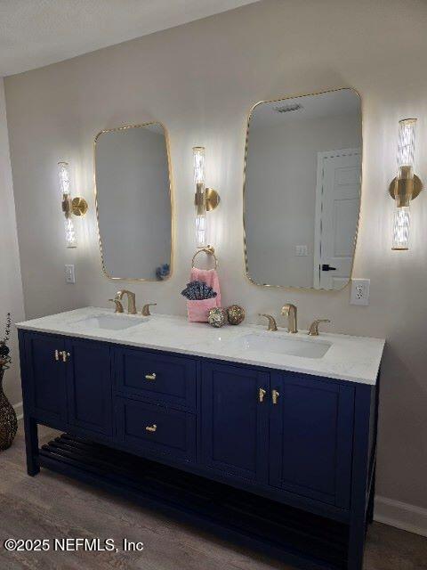 bathroom with double vanity, wood finished floors, a sink, and baseboards