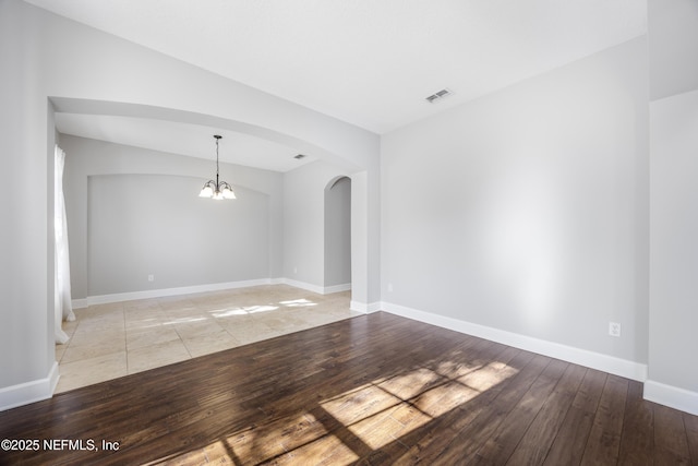 empty room featuring a chandelier and light hardwood / wood-style floors