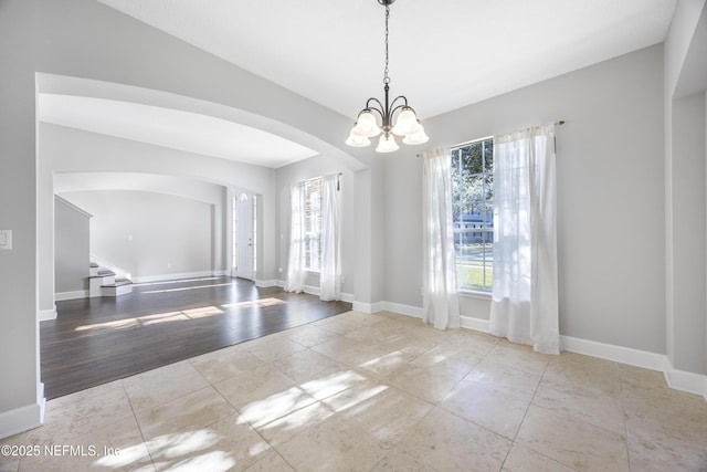 tiled empty room featuring an inviting chandelier