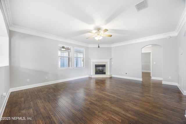 unfurnished living room with dark wood-type flooring, ceiling fan, crown molding, and a tile fireplace