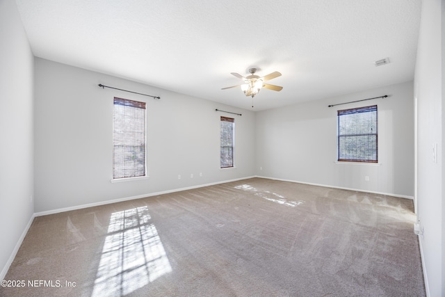 carpeted empty room featuring ceiling fan, a textured ceiling, and a healthy amount of sunlight