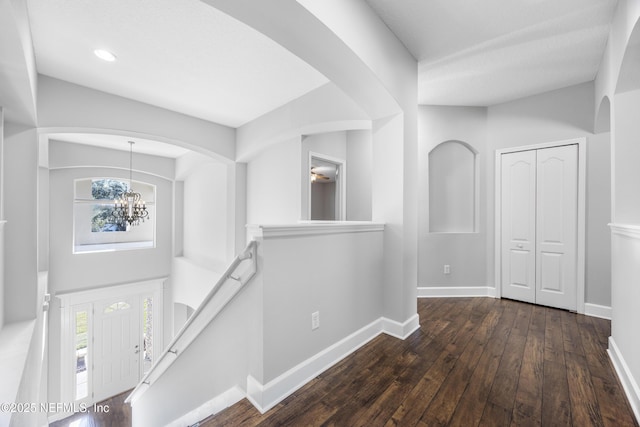 hallway featuring dark wood-type flooring and a chandelier