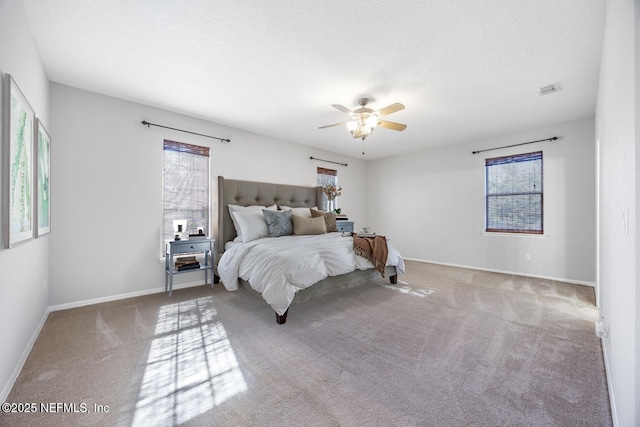 carpeted bedroom with ceiling fan and a textured ceiling