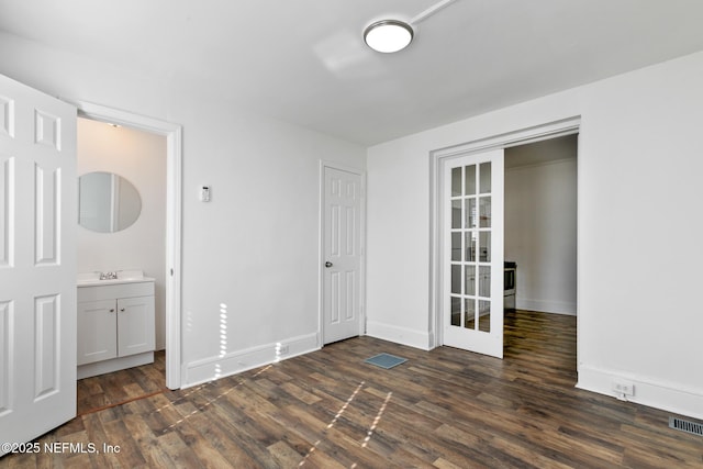 unfurnished bedroom featuring dark hardwood / wood-style flooring, ensuite bath, and french doors