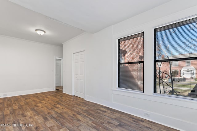 spare room with ornamental molding and dark hardwood / wood-style floors