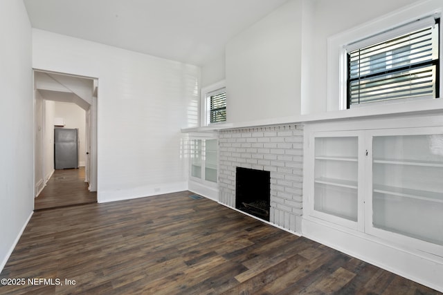 unfurnished living room with dark wood-type flooring, a fireplace, and built in shelves