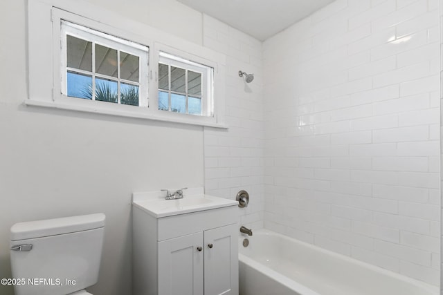 full bathroom with tiled shower / bath, vanity, and toilet