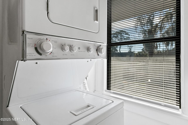 clothes washing area featuring plenty of natural light and stacked washer and clothes dryer