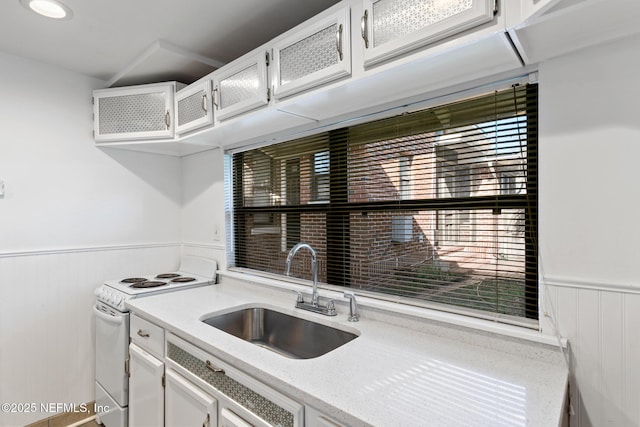 kitchen with white electric stove, white cabinetry, and sink