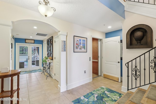 hall featuring light tile patterned floors, french doors, visible vents, and stairs