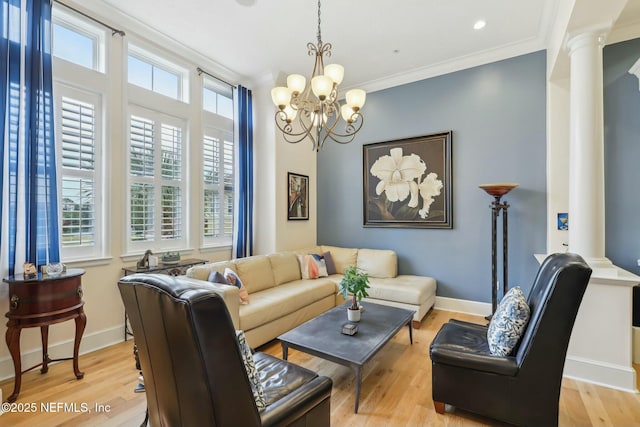 living room featuring light wood-style floors, baseboards, crown molding, and ornate columns