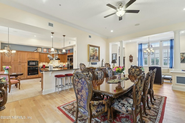 dining area with light wood-style floors, visible vents, decorative columns, and ceiling fan with notable chandelier