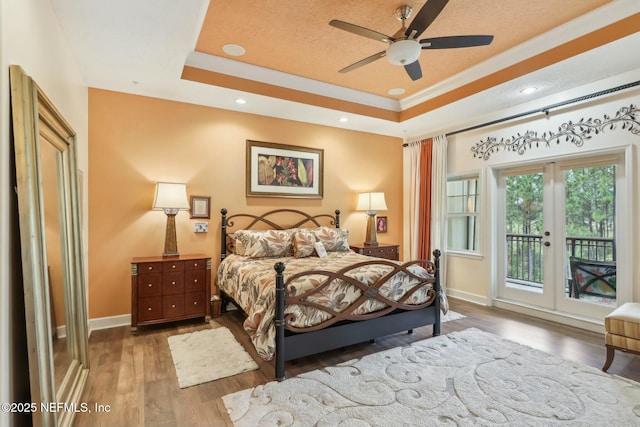 bedroom with wood finished floors, baseboards, access to exterior, french doors, and a raised ceiling