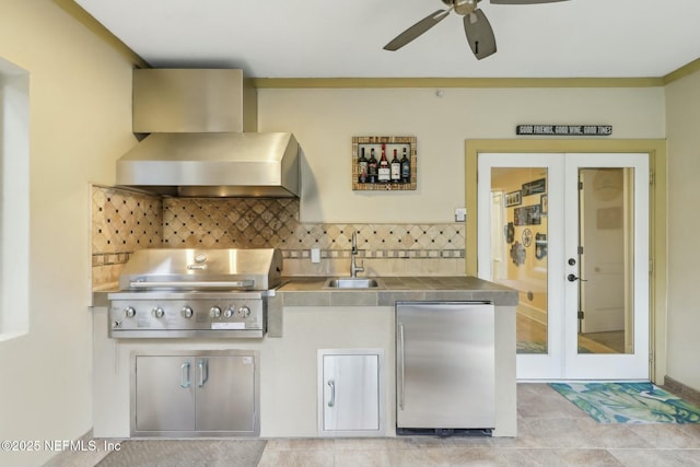 kitchen with tasteful backsplash, wall chimney exhaust hood, stainless steel refrigerator, french doors, and a sink