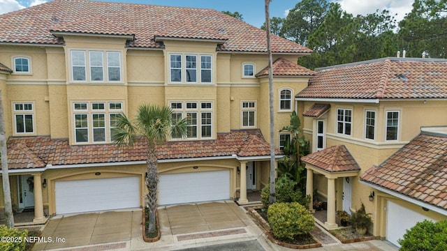 view of front facade featuring a garage, driveway, a tile roof, and stucco siding