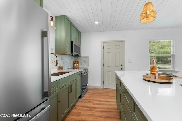 kitchen with green cabinets, decorative light fixtures, sink, decorative backsplash, and stainless steel appliances