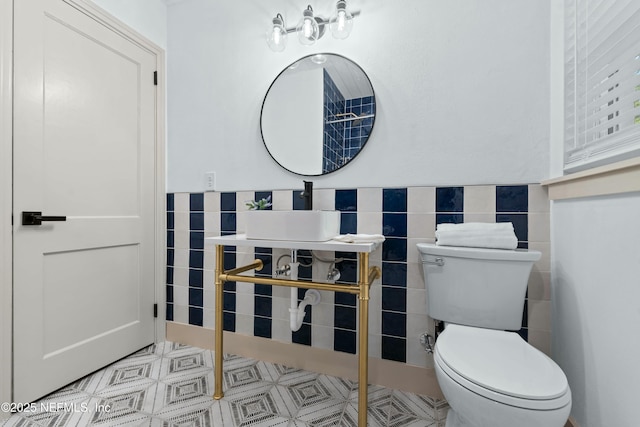 bathroom with sink, tile walls, and toilet