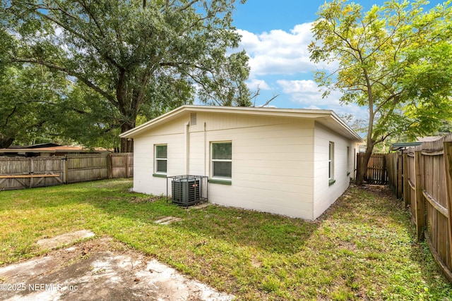 back of house with central air condition unit and a yard