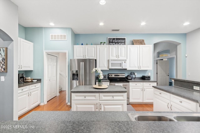 109 Bilbao Dr, Saint Augustine, FL 32086 - kitchen featuring light wood-type flooring, a kitchen island, white cabinetry, and appliances with stainless steel finishes