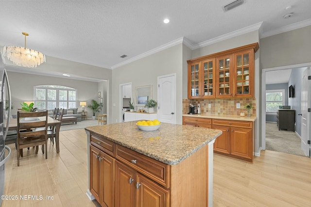 kitchen featuring pendant lighting, tasteful backsplash, a chandelier, a center island, and light hardwood / wood-style flooring