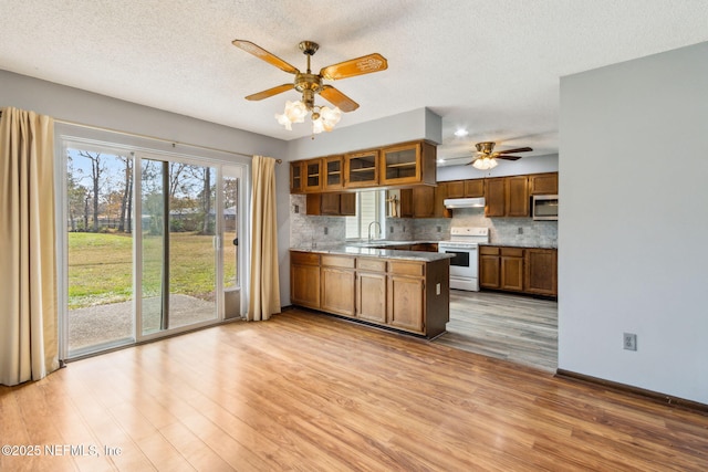 kitchen with white range with electric cooktop, sink, decorative backsplash, and light wood-type flooring